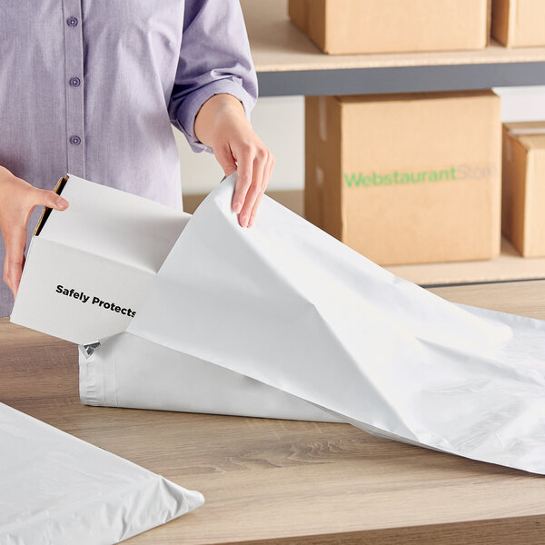 A white expandable polyethylene mailer with a tamper-evident adhesive closure being used to package a box.