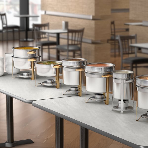 A stainless steel soup chafer with chrome accents and a gold stand, designed for serving hot soups at buffets or catered events.