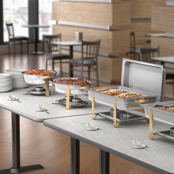 A round stainless steel chafer with gold accents used for serving hot food at buffets.