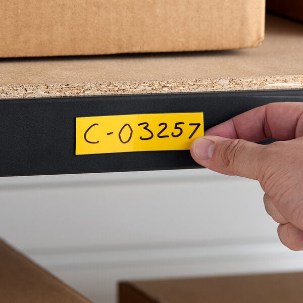 A yellow magnetic write-on label being applied to a metal shelf.