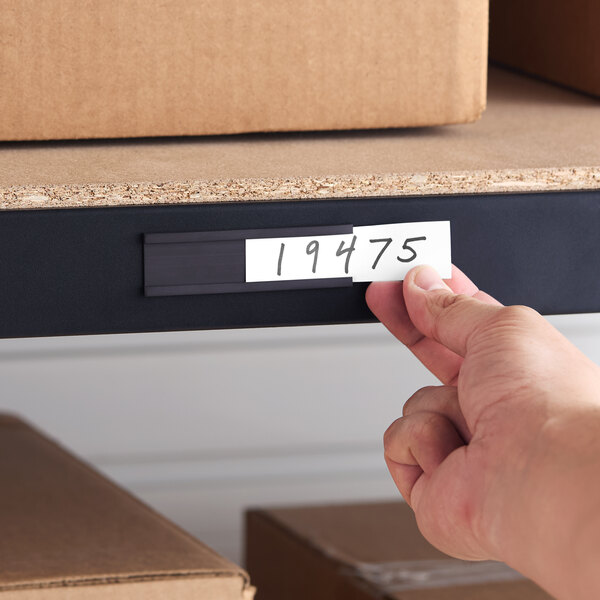 A black heavy-duty magnetic label holder with a white card inserted, attached to a metal shelf.