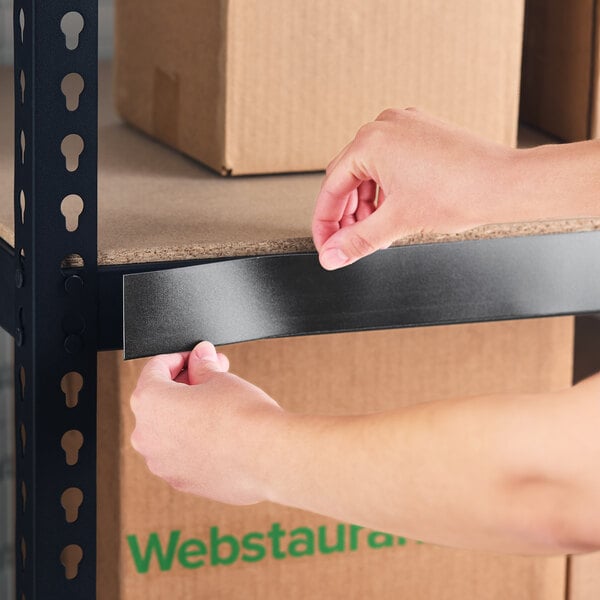 A person applying a black slip strip label holder to the edge of a metal shelving unit.
