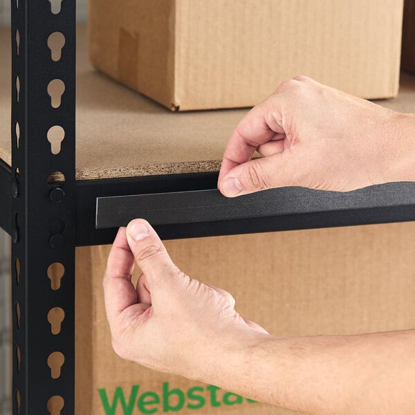 A black 1-inch by 48-inch slip strip label holder being applied to a metal shelving unit.
