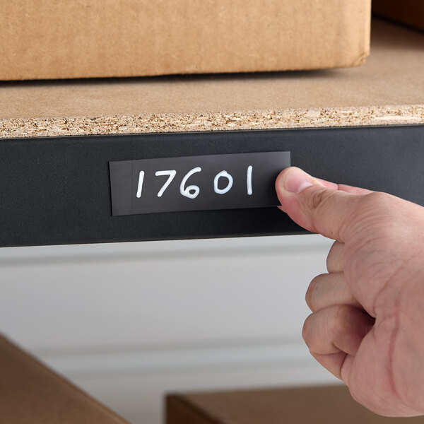 A pre-scored magnetic label holder with handwritten numbers applied to a steel shelf.