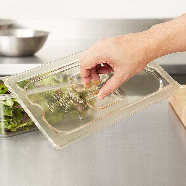 A hand holding a Vollrath Amber High Heat plastic food container full of food.