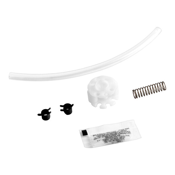A set of various small components including a clear tube, a white plastic part, a metal spring, two black clips, and a small packet, all arranged on a white background.