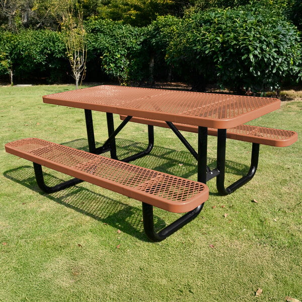 A brown expanded metal picnic table with attached benches and black metal legs, placed outdoors on grass.