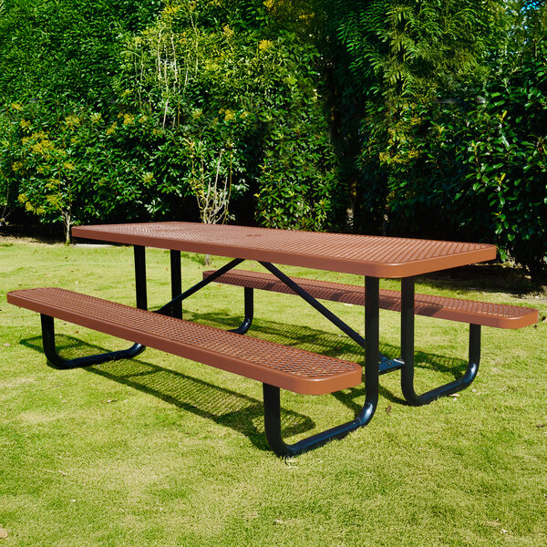 A brown expanded metal picnic table with attached benches and black metal legs, situated outdoors on grass.