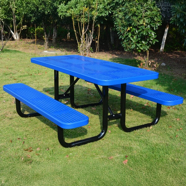 A blue perforated metal picnic table with attached benches and black metal legs, situated outdoors on grass.