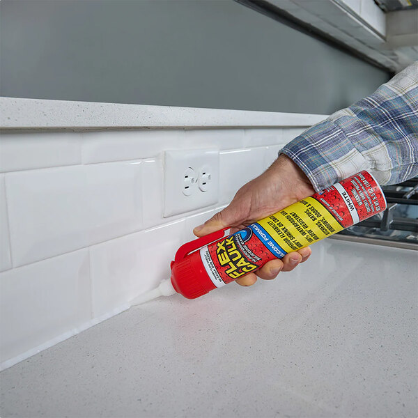 A tube of Flex Seal Flex Caulk being applied along the seam between a kitchen countertop and backsplash.