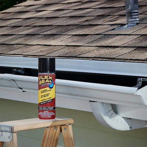A can of Flex Seal 14 oz. black liquid rubber sealant coating spray placed on a wooden ladder near a house gutter.