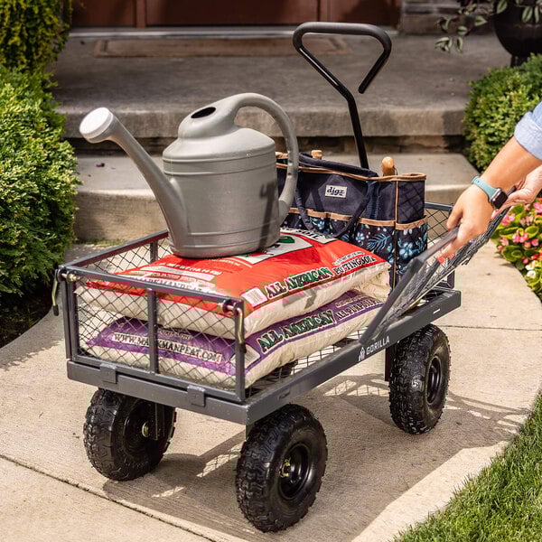 A steel utility cart loaded with gardening supplies, including bags of soil, a watering can, and a tool organizer.