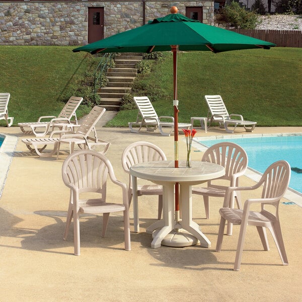 A row of white Grosfillex plastic chairs on a patio with a table.