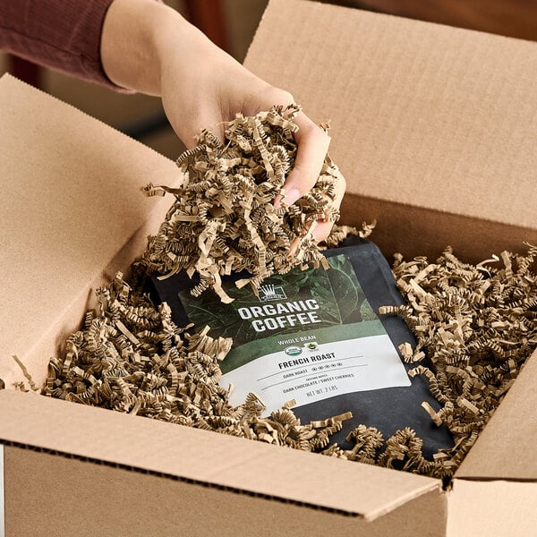 A box filled with brown kraft crinkle paper shred being used as packaging material.
