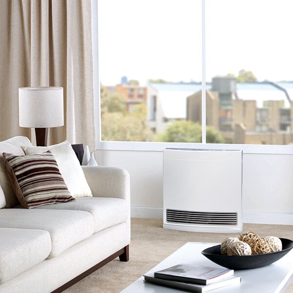 A white Rinnai liquid propane vent-free fan convection heater placed in a modern living room.