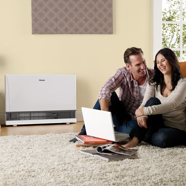 A white Rinnai EnergySaver natural gas direct-vent wall furnace placed in a living room setting.