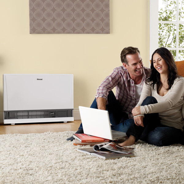 A white Rinnai EnergySaver natural gas direct-vent wall furnace placed in a living room setting.