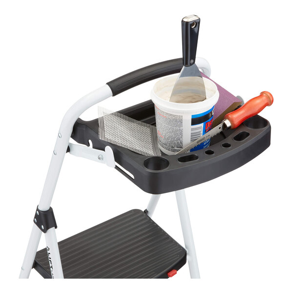 A steel 3-step folding project step stool with a built-in tray holding various tools and supplies.