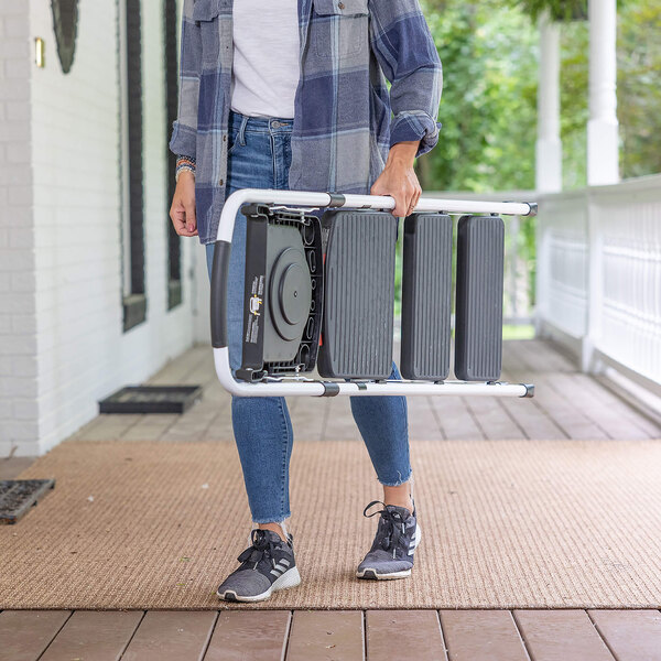 A person carrying a folded steel 3-step folding project step stool with a tray.