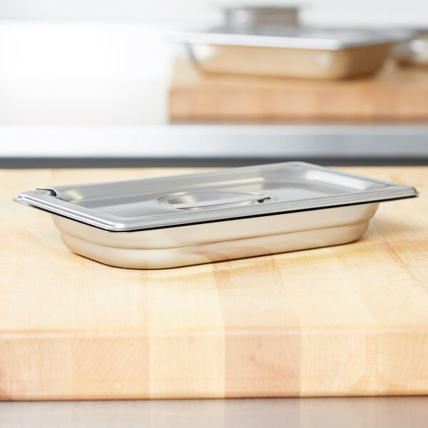 A Vollrath stainless steel slotted cover for a 1/4 size steam table pan on a wooden surface.