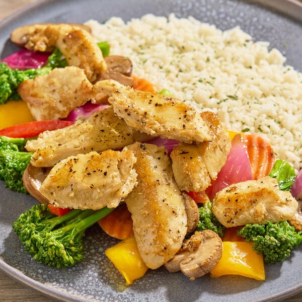 A plate of plant-based vegan chicken pieces served with mixed vegetables and a side of rice.