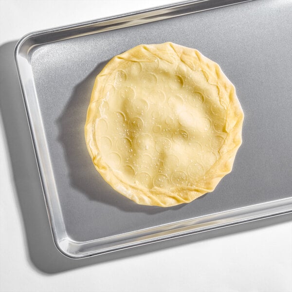 A medium-sized tarte flambee crust placed on a metal baking sheet.