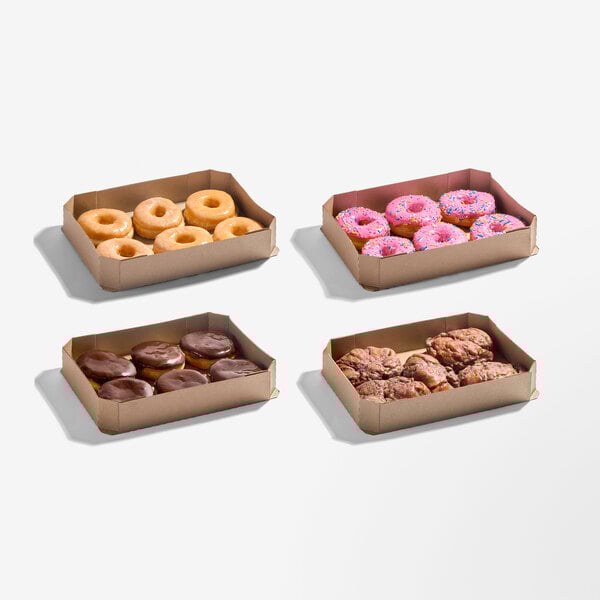 An assortment of donuts in four cardboard trays, including glazed, chocolate, pink frosted with sprinkles, and apple fritter varieties.