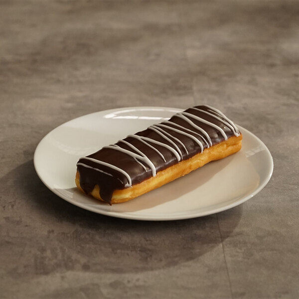 A chocolate iced buttercreme-filled long john donut with white icing drizzle on a white plate.