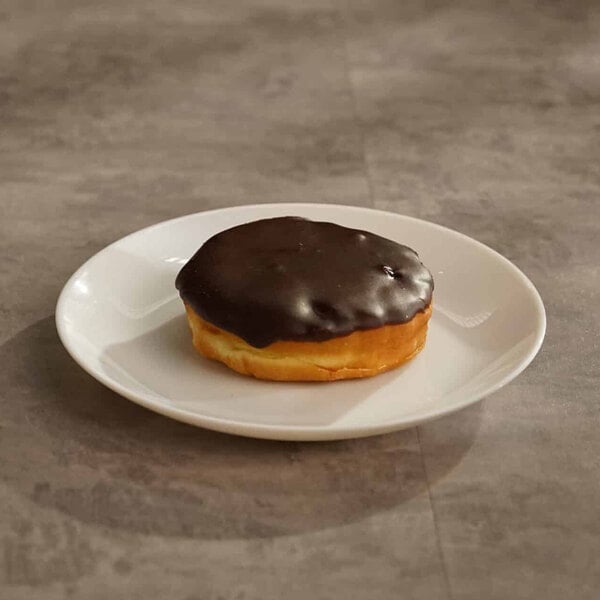 A Boston creme donut with chocolate icing on a white plate.