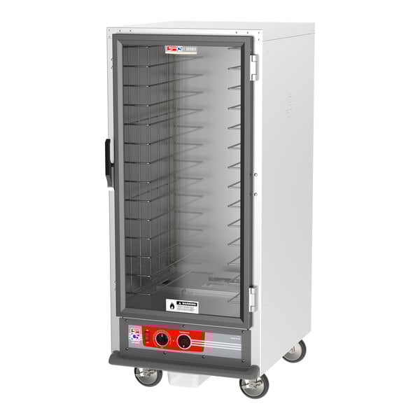 A white holding cabinet with a clear glass door on wheels.