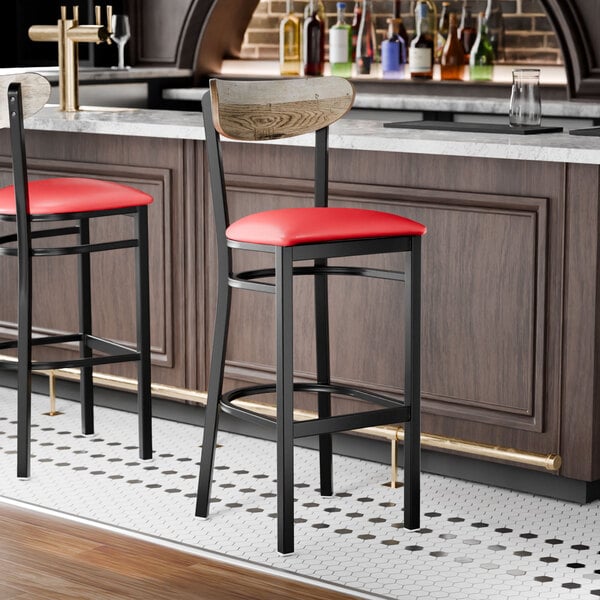 A black bar stool with a red vinyl seat and a driftwood-finished wooden backrest.