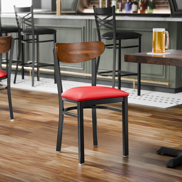 A black metal chair with a red vinyl seat and a curved vintage wood backrest.