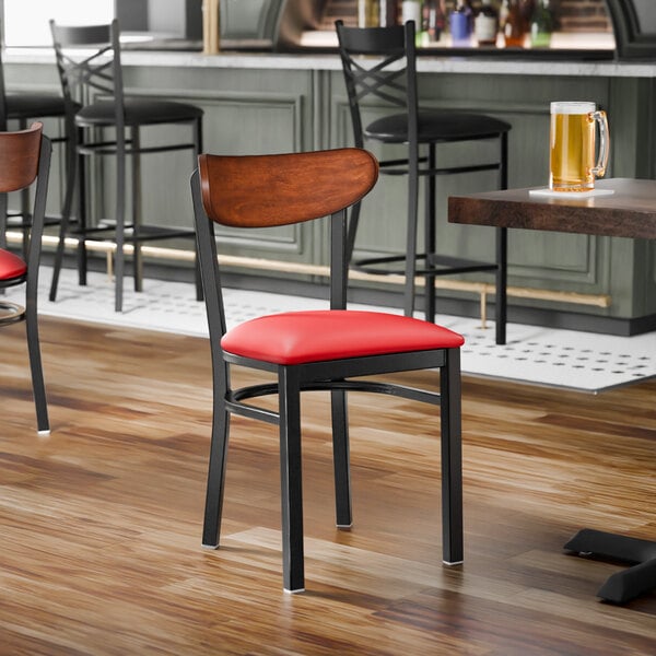A black metal chair with a red vinyl seat and an antique walnut wood backrest.