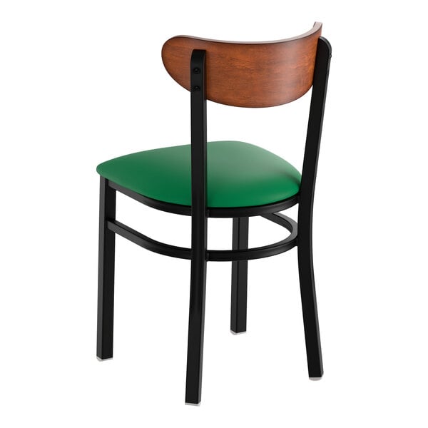 A black metal chair with a green vinyl seat and an antique walnut wood backrest.