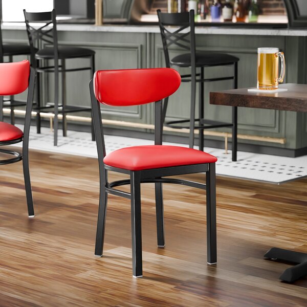 A black metal chair with a red vinyl seat and backrest, shown unassembled.