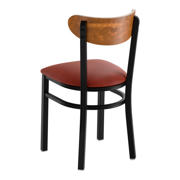 A black metal chair with a burgundy vinyl seat and a curved vintage wood backrest.