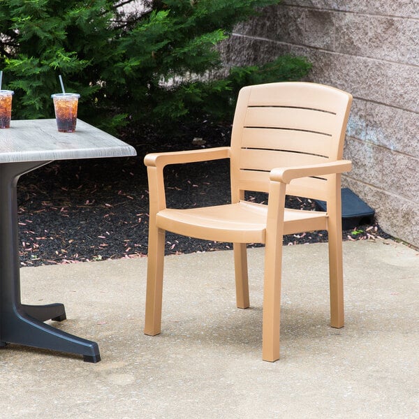 A tan Grosfillex plastic chair on a concrete patio.