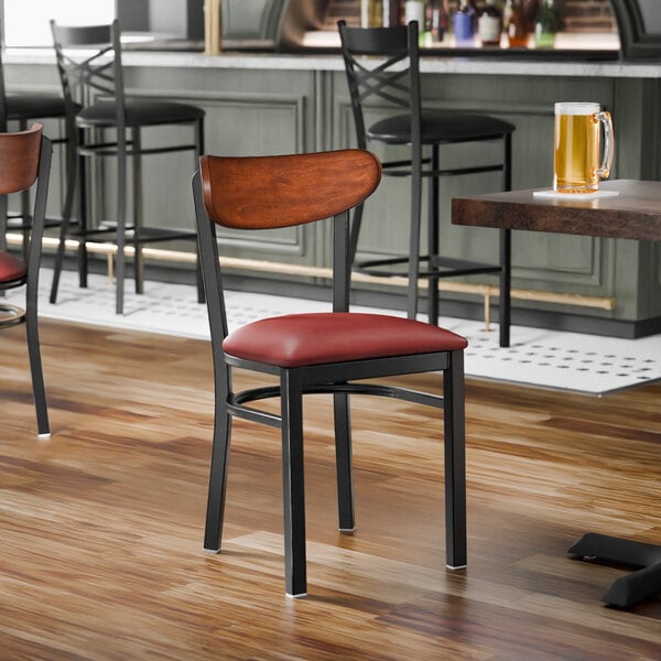 A black metal chair with a burgundy vinyl seat and an antique walnut wood backrest.