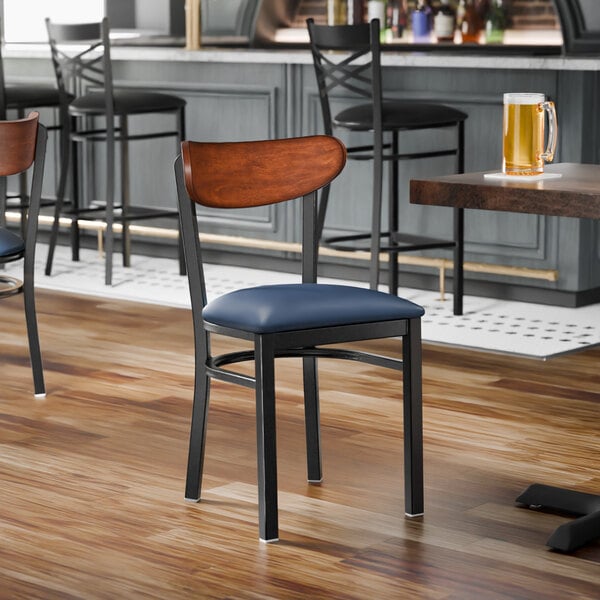 A black metal chair with a navy vinyl seat and an antique walnut wood backrest, shown unassembled.