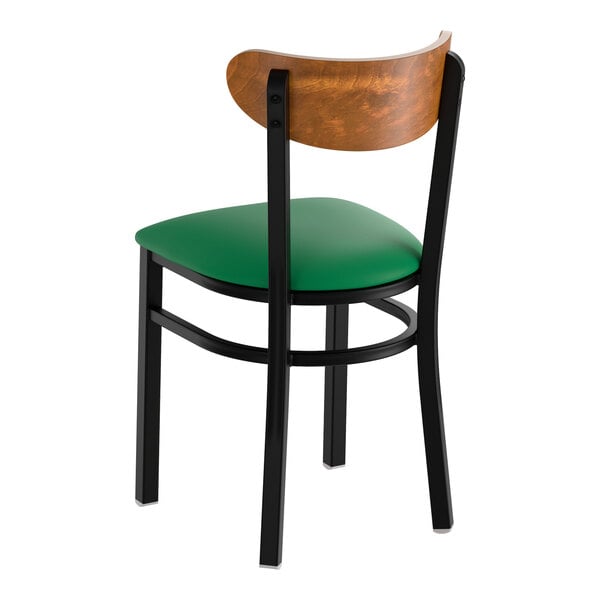 A black metal chair with a green vinyl seat and a curved vintage wood backrest.