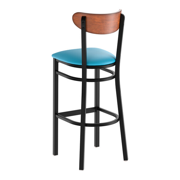 A black metal bar stool with a blue vinyl seat and an antique walnut wood backrest.