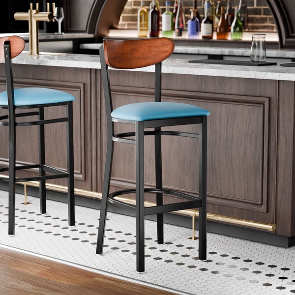 A black finish bar stool with a blue vinyl seat and an antique walnut wood back.