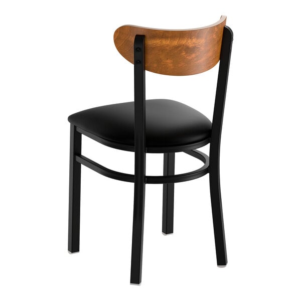 A black metal chair with a black vinyl seat and a curved vintage wood backrest.