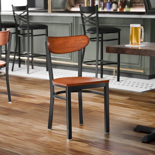 A black metal chair with an antique walnut wood seat and back, shown unassembled.