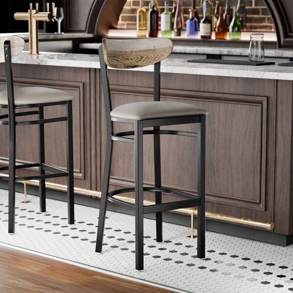A black bar stool with a dark gray vinyl seat and a driftwood-finished wooden backrest.