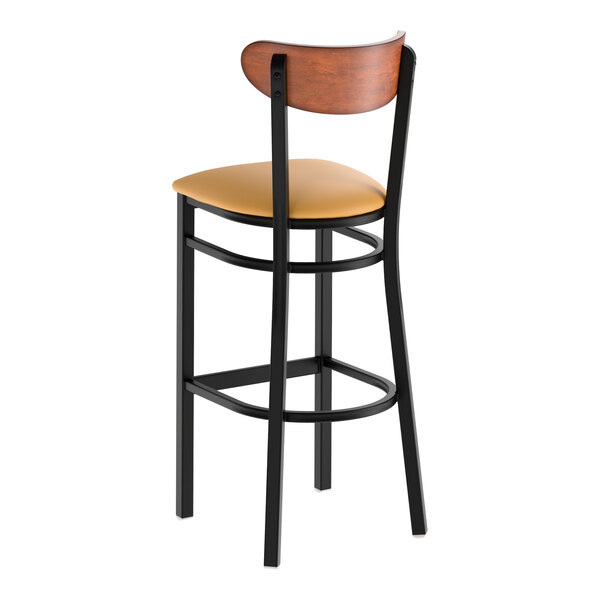 A bar stool with a black metal frame, light brown vinyl seat, and an antique walnut wood backrest.
