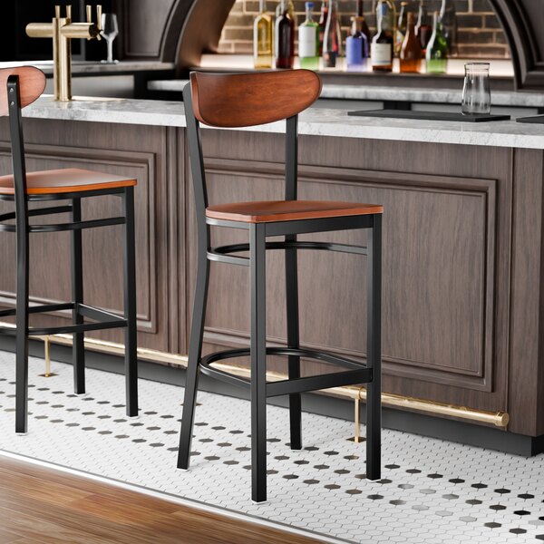 A black finish bar stool with an antique walnut wood seat and back.