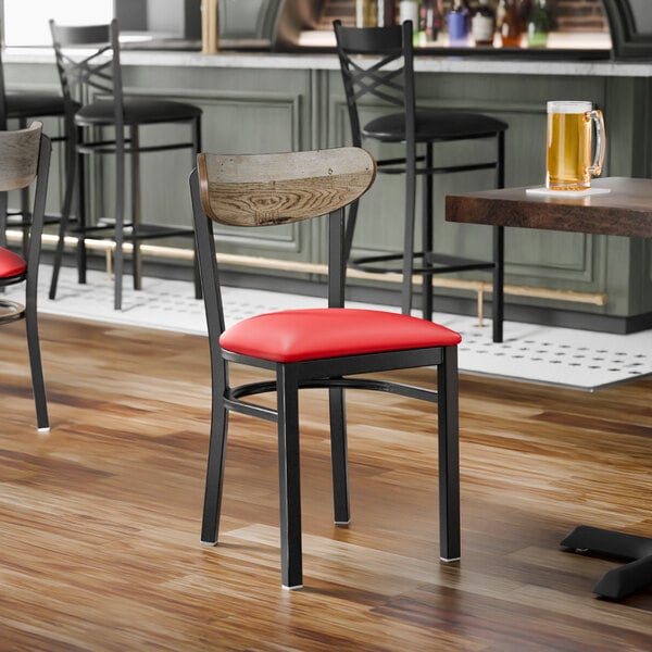 A black metal chair with a red vinyl seat and a driftwood-finished wooden backrest.