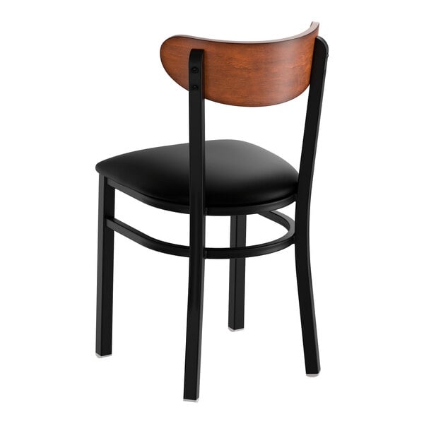 A black metal chair with a black vinyl seat and an antique walnut wood backrest.