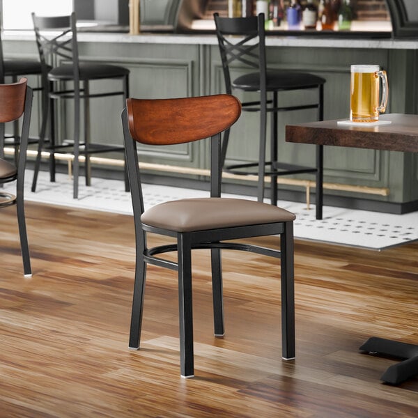 A black metal chair with a taupe vinyl seat and an antique walnut wood backrest.